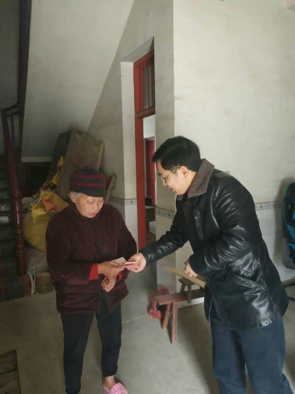 图为县委巡察组组长邓喜平(右)给贫困群众送去慰问金